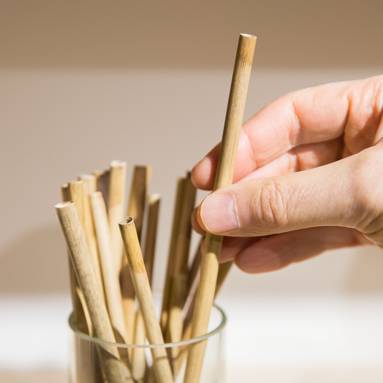 Man Holding Bamboo Straw in a Glass Cylinder